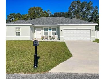 Charming single-story home featuring a well-manicured lawn and a two-car garage on a sunny day at 15954 Sw 55Th Avenue Rd, Ocala, FL 34473