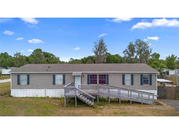 Charming single-story home with blue shutters, gray siding, and a ramp leading to the front door at 18806 Monroe Ave, Orlando, FL 32820