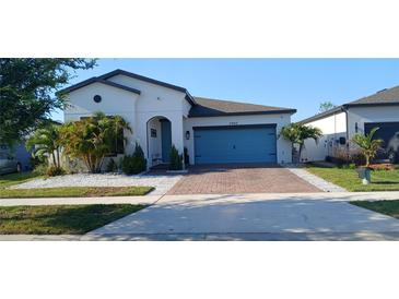 Charming single-story home featuring a blue garage door, brick driveway, and well-manicured landscaping at 2950 Scarlett Dr, St Cloud, FL 34772