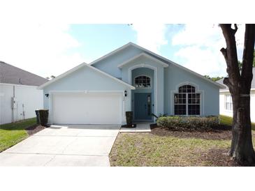 Charming one-story home features a two-car garage, manicured lawn, and beautiful windows at 334 Grosvenor Loop, Davenport, FL 33897