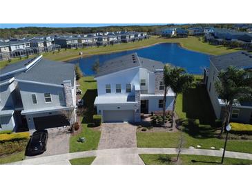 Beautiful two-story home with stone accents, a brick driveway, and a serene water view at 345 Ocean Course Ave, Davenport, FL 33896
