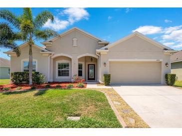 Charming single-story home featuring a well-manicured lawn, palm tree, and neutral-toned facade at 3894 Wind Dancer Cir, St Cloud, FL 34772