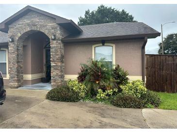 Charming single-story home features a stone archway entrance and mature landscaping, enhancing its curb appeal at 5719 Sweetheart Ct, St Cloud, FL 34772