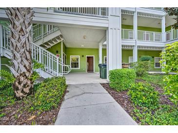 Inviting condo exterior featuring green siding, white trim, and well-maintained landscaping at 702 Gran Bahama Blvd, Davenport, FL 33897