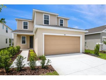 Charming two-story home featuring an attached two-car garage, manicured lawn, and beautiful landscaping at 808 Lake Dell Rd, Dundee, FL 33838