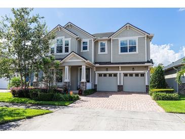Charming two-story home with a three-car garage, brick-paved driveway, and manicured landscaping at 8228 Randal Park Blvd, Orlando, FL 32832