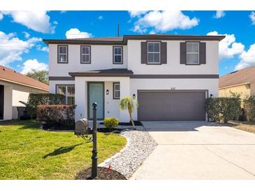 Charming two-story home featuring a well-maintained lawn, a two car garage, and an inviting entrance at 227 Sand Ridge Drive, Davenport, FL 33896