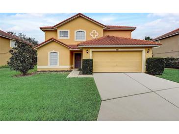 Inviting two-story home with a well-manicured lawn and a two-car garage, painted in warm, earthy tones at 253 Granada Blvd, Davenport, FL 33837