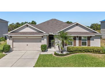 Charming single-story home featuring a well-manicured lawn, two car garage, and neutral colored stucco at 5759 Marsh Landing Dr, Winter Haven, FL 33881