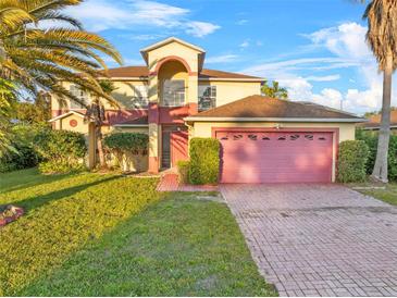 Charming home boasts a well-maintained lawn, arched entry, and a pink two-car garage at 638 Kangaroo Dr, Poinciana, FL 34759