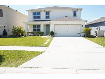 Charming two-story home featuring a well-manicured lawn and a convenient two-car garage at 9016 Pyrus St, Kissimmee, FL 34747