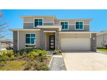 Contemporary two-story home featuring a two-car garage, stone accents and manicured landscaping at 1003 Sugarwood St, Davenport, FL 33837
