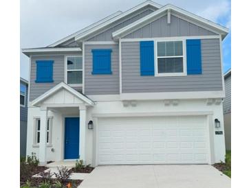 Charming two-story home features a gray facade with bright blue shutters and a white garage door at 1796 Foreman Rd, Eagle Lake, FL 33839