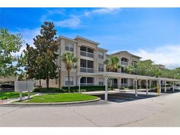 Lovely condo complex with covered parking, lush landscaping, and light stucco exterior at 3025 Greystone Loop # 302, Kissimmee, FL 34741