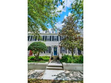 Charming townhome featuring a blue front door with a wreath, flanked by lush greenery and trees at 541 Campus St, Celebration, FL 34747