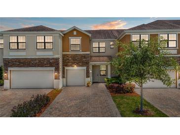 Inviting townhome with brick driveway, two-car garage, and well-maintained landscaping at 1809 Portofino Meadows Blvd, Orlando, FL 32824