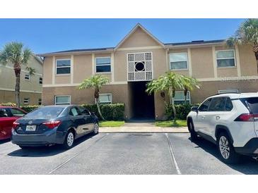 Tan two-story condo building with a decorative facade and lush palm trees at 2408 Barley Club Ct # 2, Orlando, FL 32837