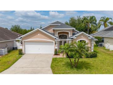 Charming home with a well-manicured lawn, palm trees, and a two-car garage, offering curb appeal at 301 Wingdale Way, Davenport, FL 33897