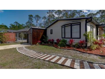 Charming single-story home with a stone and wood path, vibrant landscaping, and a detached garage at 3669 General Marshall Rd, Daytona Beach, FL 32124