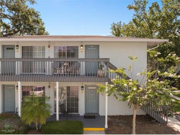 Charming two-story condo featuring gray paint, a balcony, and a well-maintained front yard with mature landscaping at 4820 Conway Rd # 130, Orlando, FL 32812