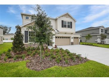 Two-story home featuring a three-car garage, stone accents, and freshly installed landscaping at 1019 Cloud Ridge Ct, Mount Dora, FL 32757