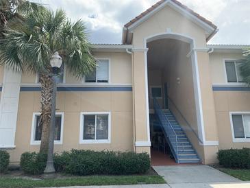 Inviting two-story exterior featuring a well-maintained lawn, blue accents and a prominent palm tree at 13226 Galicia St # 103, Orlando, FL 32824
