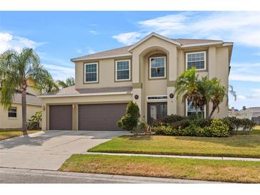 Two-story stucco home featuring a three-car garage, manicured lawn, and beautiful landscaping at 2005 Pitch Way, Kissimmee, FL 34746