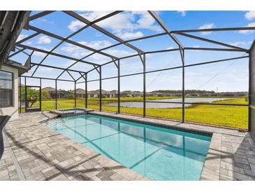 Sparkling pool with spa and screened enclosure overlooking the serene lake and community at 249 Bella Cortina Dr, Kissimmee, FL 34759