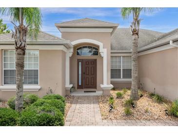 Elegant entryway featuring a dark wood door, decorative columns, and lush landscaping at 308 Yellow Snapdragon Dr, Davenport, FL 33837