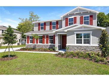 Charming two-story home with red shutters and stone accents surrounded by a lush, green lawn at 3765 Deer Ridge Dr, Mount Dora, FL 32757