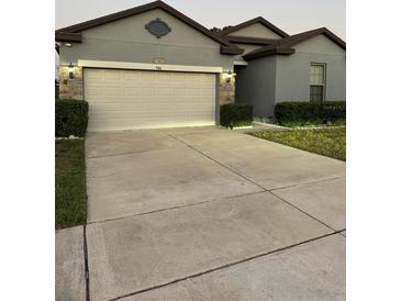 Charming home exterior with well-maintained lawn, landscaping, and a two-car garage at 748 Citrus Isle Dr, Davenport, FL 33837