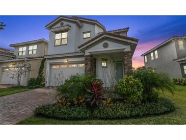Charming two-story home with a tile roof, stone accents, manicured landscaping, and a two-car garage at 13282 Bromborough Dr, Orlando, FL 32832