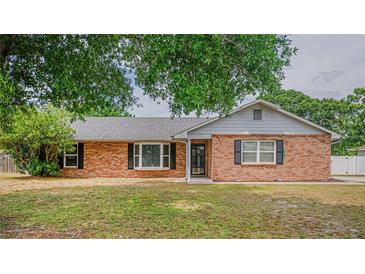 Charming brick home featuring black shutters and a well-maintained front yard, shaded by a mature tree at 1700 E Clinton Dr, St Cloud, FL 34769