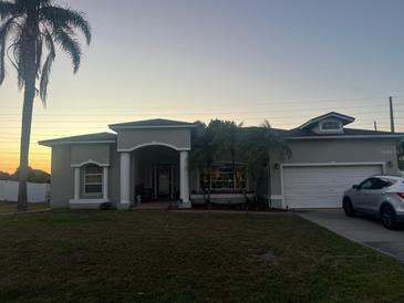 Charming single-story home with a well-manicured lawn, mature palm trees, and a covered front porch at 1920 Triumfo Cir, Kissimmee, FL 34744