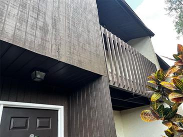 Low angle view of a two-story exterior featuring stained wood and a balcony with paneled rails at 2659 Crown Ct # 11, Kissimmee, FL 34741