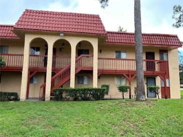 Multi-Gathering exterior features red tile roof, tan stucco, red painted stairs and railings, and tidy landscaping at 2804 N Powers Dr # 31, Orlando, FL 32818
