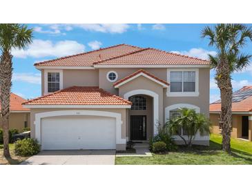 Beautiful two-story home featuring a tile roof, arched entryway, palm trees, and a well-maintained front lawn at 301 Rosso Dr, Davenport, FL 33837