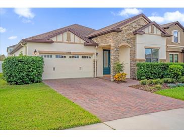 Charming single-story home featuring a stone facade, well-manicured landscaping and brick paver driveway at 3366 Puxton Dr, Orlando, FL 32824