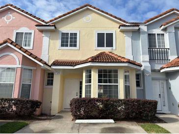 Charming yellow townhouse featuring a terra cotta roof, bay window, and well-maintained landscaping at 4726 Hemingway House St, Kissimmee, FL 34746