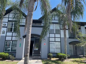 A charming, two-story condo building with palm trees and visible stairs to upper units at 5501 G Nw Ave # 4714, Orlando, FL 32815