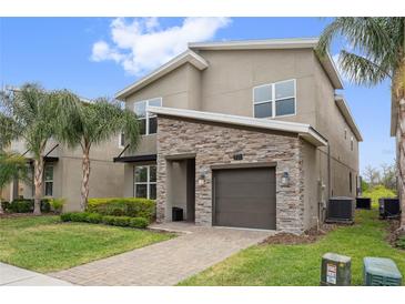 Charming two-story home featuring a stone accent facade, well-manicured lawn, and a paver driveway at 721 Drop Shot Dr, Davenport, FL 33896