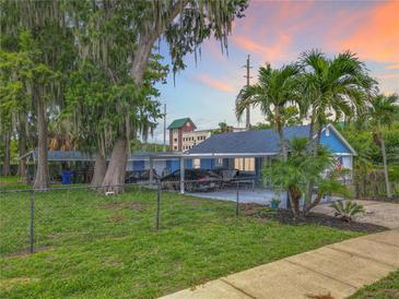 Charming light blue home with lush greenery, a carport, and a chain-link fence at 302 E Drury Ave, Kissimmee, FL 34744