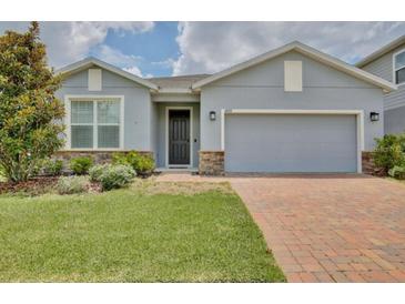 Charming single-story home with a brick driveway, stone accents, and lush landscaping at 4327 Silver Creek St, Kissimmee, FL 34744