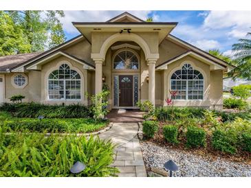 Inviting front entrance featuring an arched doorway, columns, and lush landscaping at 154 Academy Oaks Pl, Altamonte Springs, FL 32714
