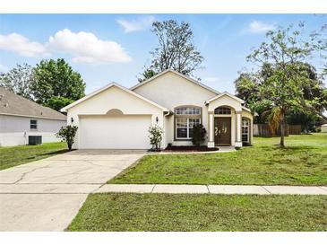 Charming one-story home featuring a manicured lawn and attached two-car garage at 1823 Ashton E Dr, St Cloud, FL 34771