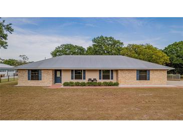 Charming brick home with a modern metal roof, complemented by blue shutters and a well-manicured front lawn at 4091 Lippman Rd, St Cloud, FL 34772