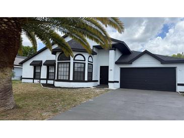 Charming home featuring a clean white exterior and dark accents, along with an attached two-car garage at 414 Otter Creek Dr, Kissimmee, FL 34743