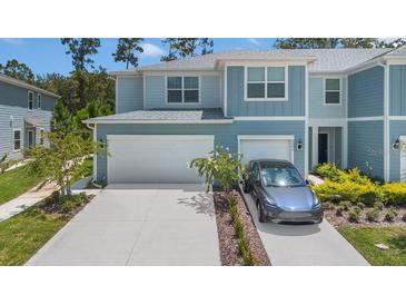 Charming two-story townhouse with a two car garage, manicured lawn, and a Tesla parked in the driveway at 4542 Cypress Cay Way, Kissimmee, FL 34746