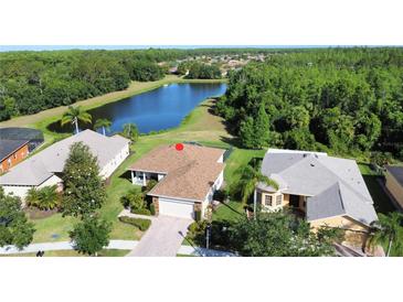 Aerial view of a single-story home featuring lush landscaping and a tranquil lake backdrop at 650 Portofino Drive, Poinciana, FL 34759
