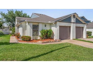Charming single-story home features a well-manicured lawn and an attached two-car garage with mature flowering landscaping at 98 Lakepointe Cir, Kissimmee, FL 34743